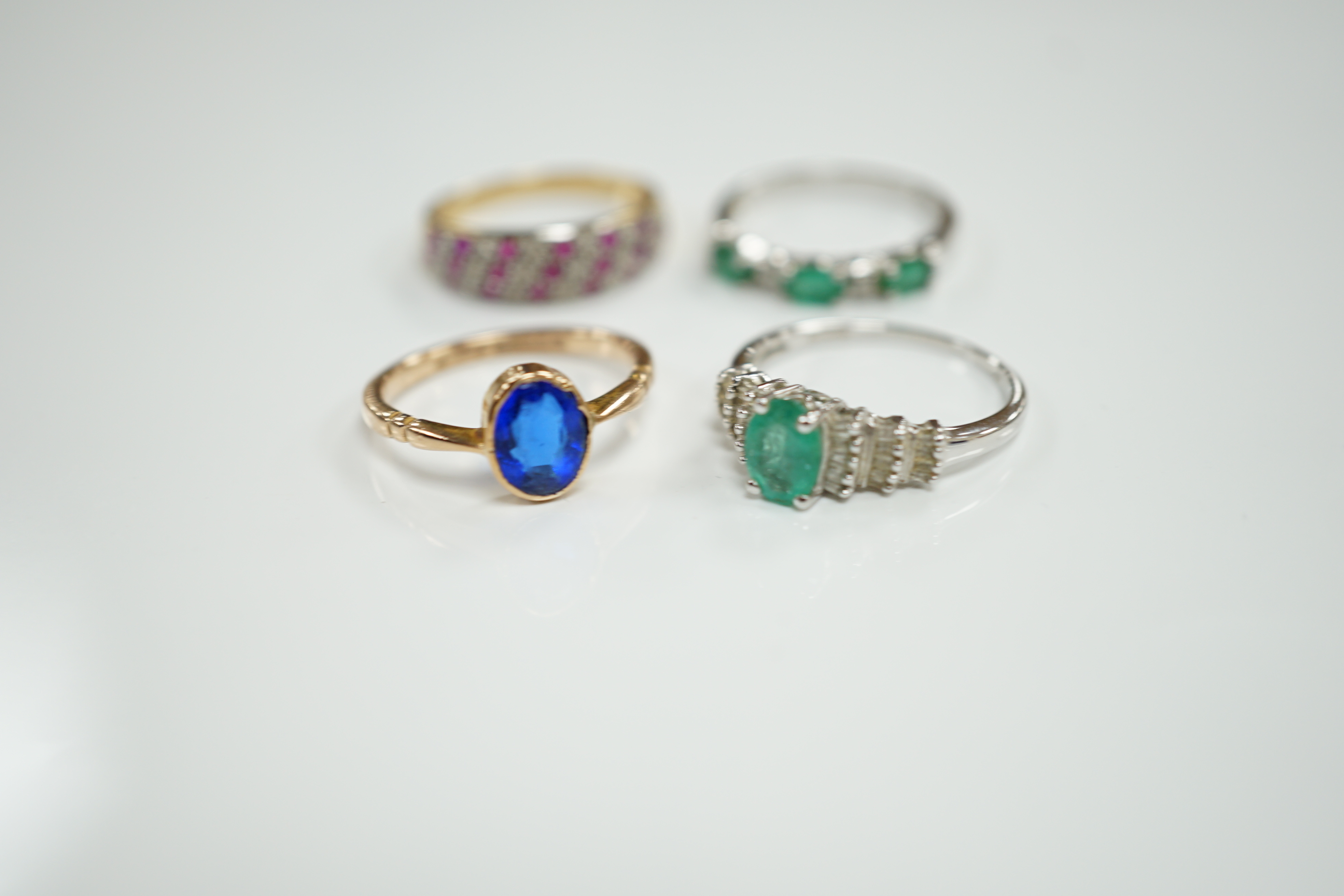 Three assorted modern 9ct gold and gem set rings including emerald and diamond chip set half hoop, size N, gross weight 6.8 grams and a modern14ct white gold and single stone emerald set dress ring, with baguette cut dia